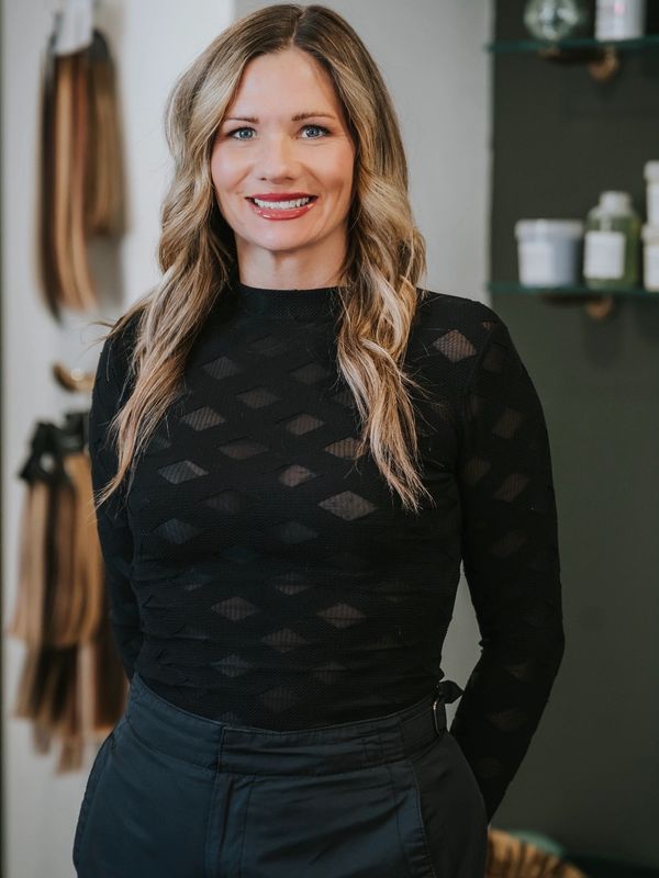 A smiling woman with blonde hair wearing a black top.