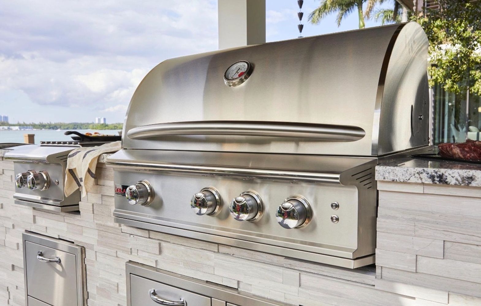 Sleek stainless steel outdoor grill setup with knobs and temperature gauge.