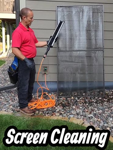 Man cleaning a large screen with a power tool outside a house.