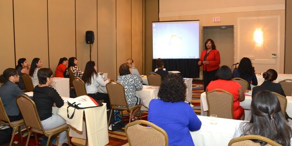 Woman presenting to audience in conference room.