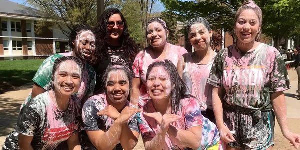 Group of friends covered in powder smiling outdoors.