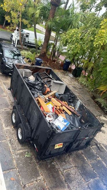 A large black trailer filled with various discarded materials and debris.