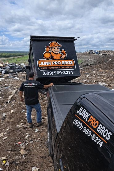 Worker loading a Junk Pro Bros truck at a junk removal site.