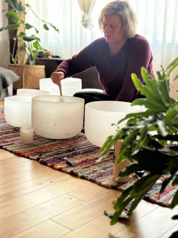 Person playing large white crystal singing bowls.