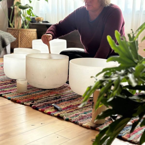 Person playing large white crystal singing bowls.