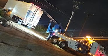 A tow truck recovering a large trailer at night.