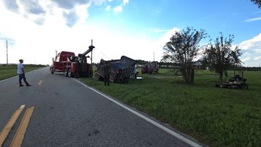 Tow trucks recovering a tipped dump truck by the roadside.