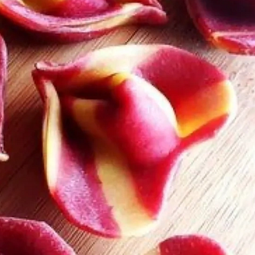 Colorful striped tortellini pasta on a wooden surface.