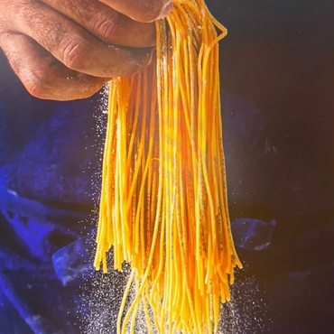 Hand holding fresh pasta with flour falling down.