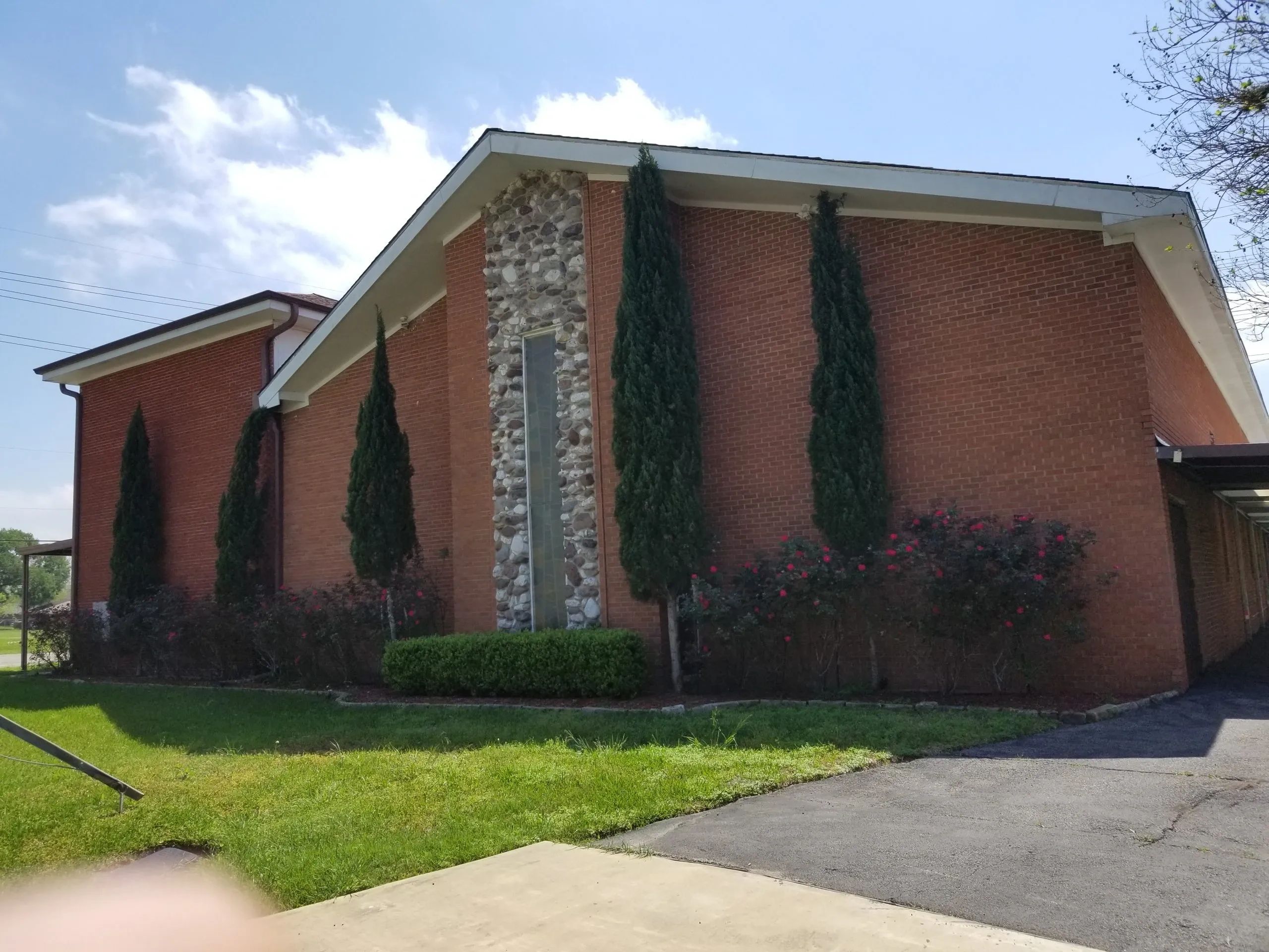 Brick building with tall trees and a stone chimney under a clear sky.