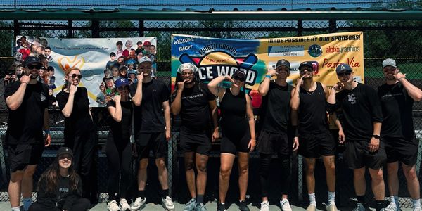Group of people in black outfits holding medals, celebrating at an outdoor sports event.