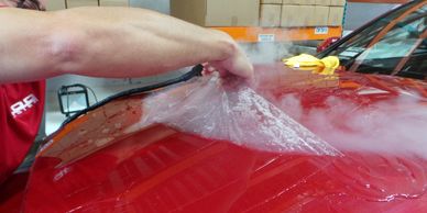 a man waxing a red car in a garage