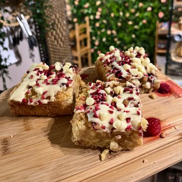 Three square dessert bars topped with white chocolate chips and red sprinkles on a wooden board.