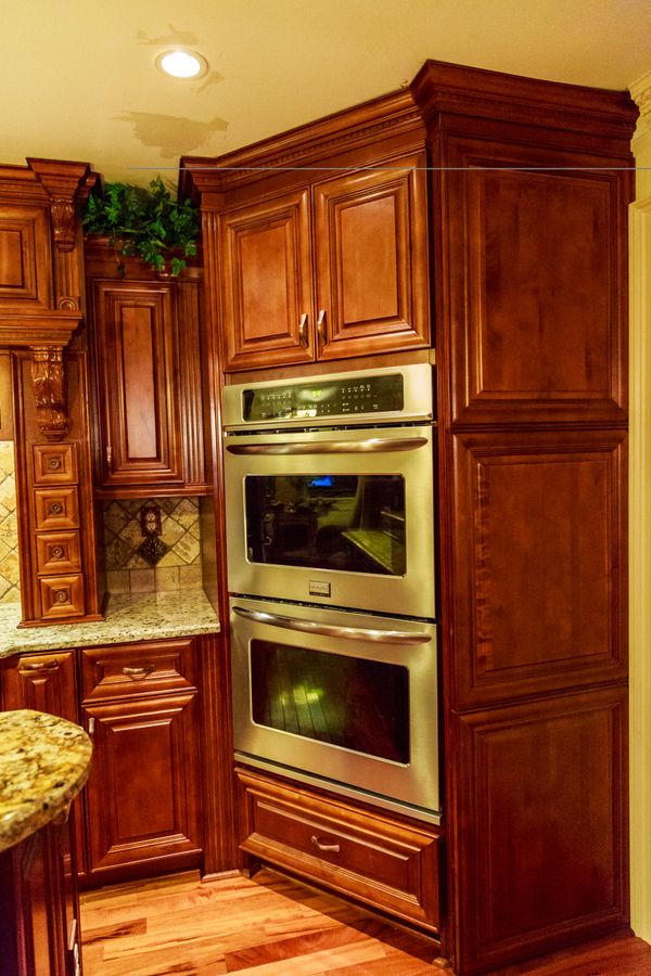 Double stainless steel oven built into rich wooden cabinetry.