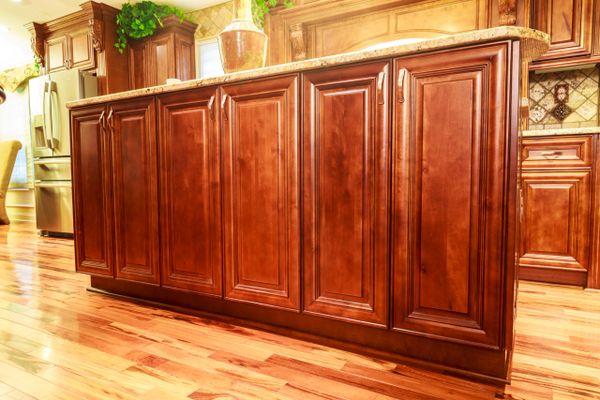 Polished wooden kitchen cabinets with granite countertop and hardwood floor.