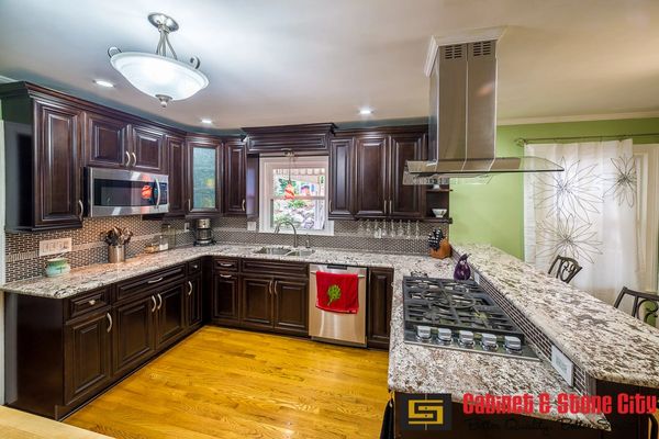 Modern kitchen with dark wood cabinets and granite countertops.