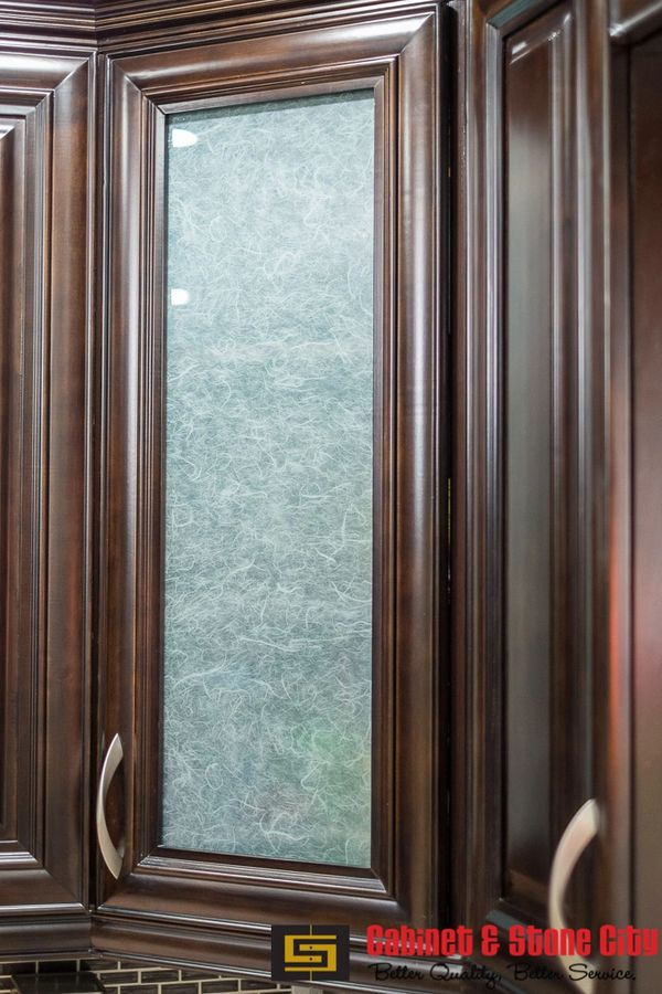 Dark wood kitchen cabinet with frosted glass panel and silver handle.