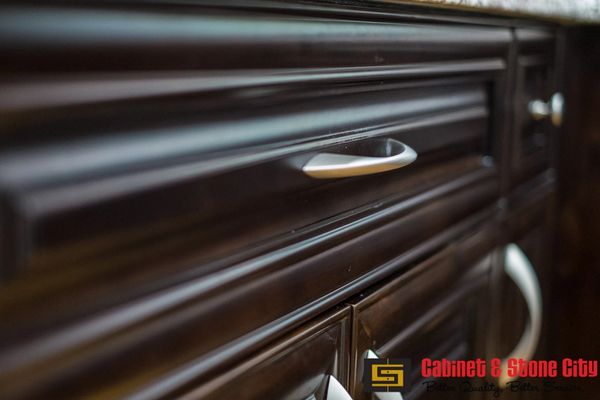 Close-up of a dark wooden cabinet drawer with a silver handle.