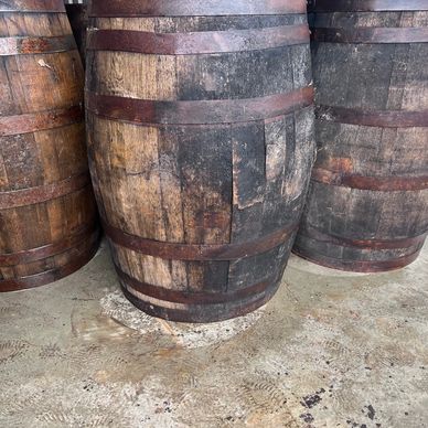 Three old wooden barrels with metal bands on a concrete floor.