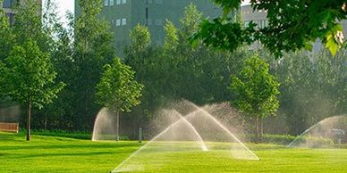 Image of sprinklers watering grass at a commercial building site.