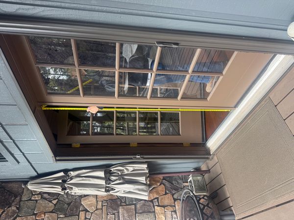 Person measuring a door frame with a tape measure at a cabin.