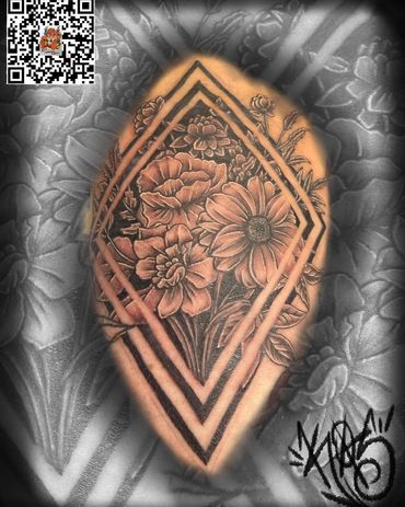 Intricate floral tattoo framed by double diamond shapes on skin.