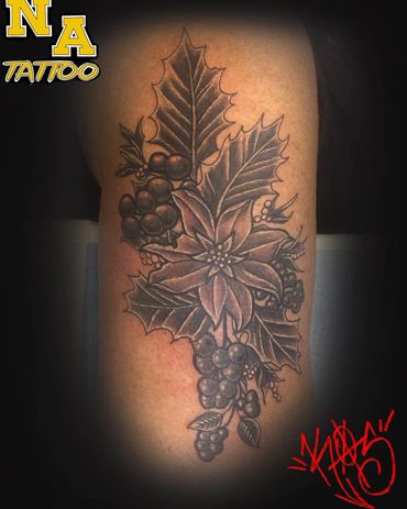 Black and grey tattoo of holly leaves and berries with a flower on skin.