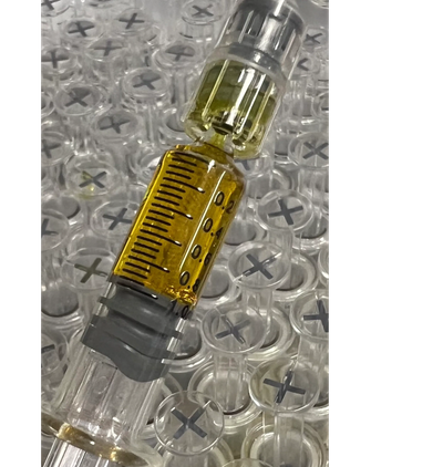Close-up of a syringe filled with yellow liquid on a background of clear plastic caps.