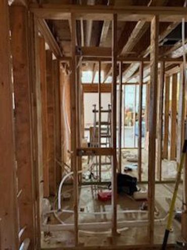 Interior wooden framing of a house under construction with exposed studs and wiring.
