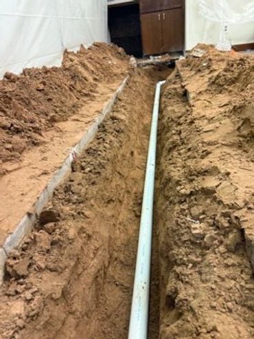 A trench with a white pipe laid in the middle of it.