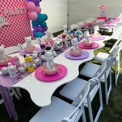 Kids' painting party setup with colorful balloons and supplies.