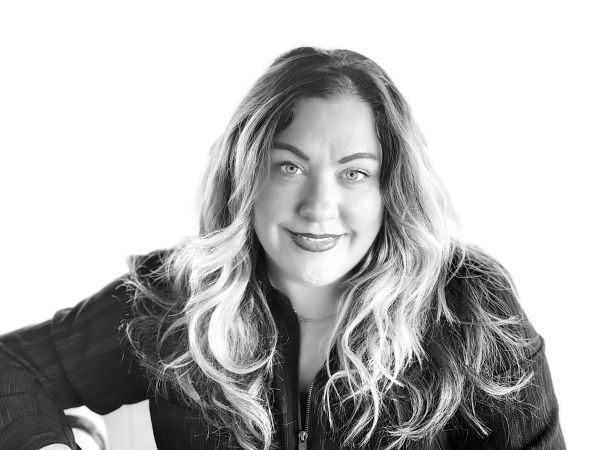 Black and white portrait of a woman with long wavy hair and a confident smile.