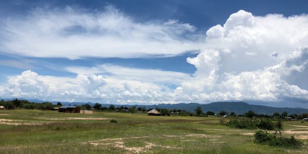 Rural landscape with scattered houses under a cloudy blue sky.
