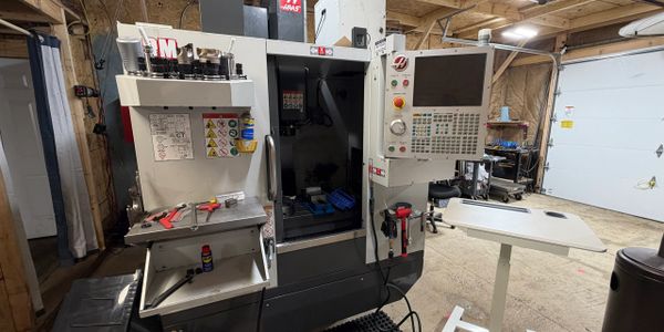 Industrial CNC milling machine in a workshop with tools and materials nearby.