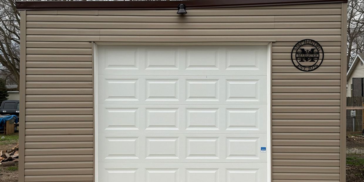 A beige garage with a white door and a decorative sign on the right side.