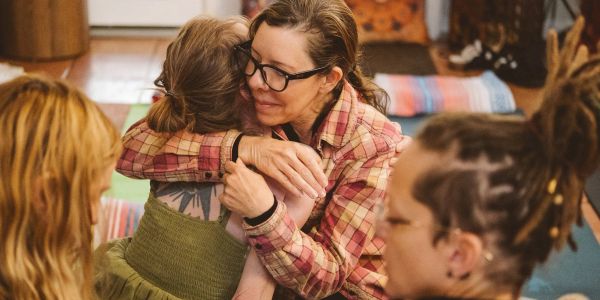 Two women warmly hugging in a cozy indoor setting.