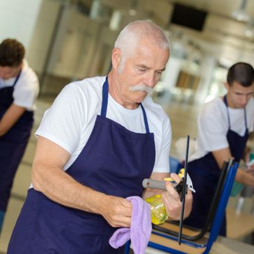 Three janitors cleaning a modern building wearing aprons.