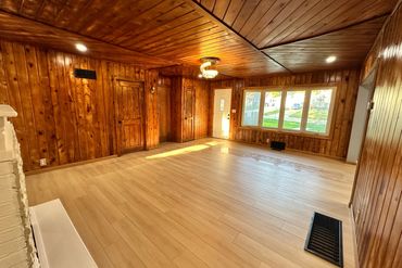 Empty room with wood-paneled walls and light wooden floor.