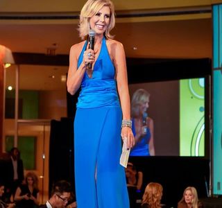 Michelle Schoenfeld Keynote speaker on large stage with microphone in blue dress,  best motivational speakers