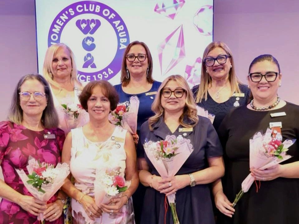 Group of women holding flowers at Women's Club of Aruba event.