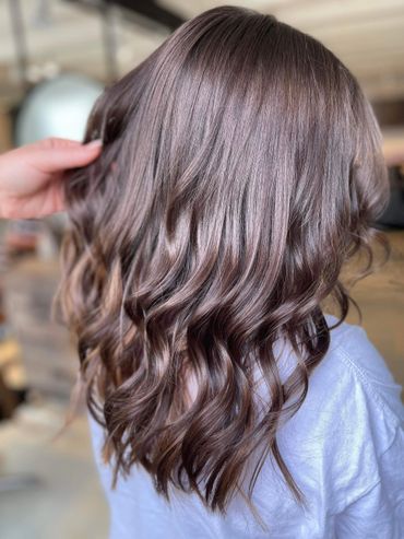 Shiny, wavy brown hair styled with loose curls.