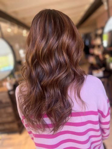 Shiny wavy chestnut brown hair cascading down the back.