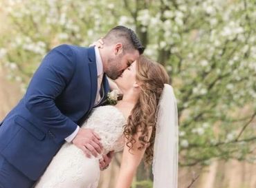 Bride and groom share a romantic kiss outdoors on their wedding day.