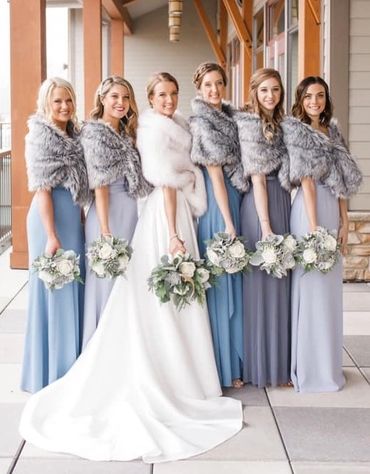 Bride and bridesmaids in elegant dresses with fur stoles and bouquets.