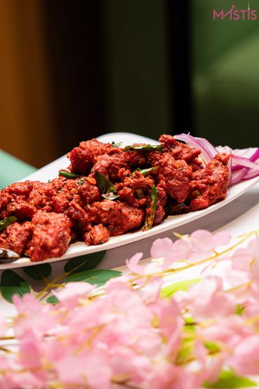 Spicy fried chicken pieces garnished with curry leaves and sliced onions.