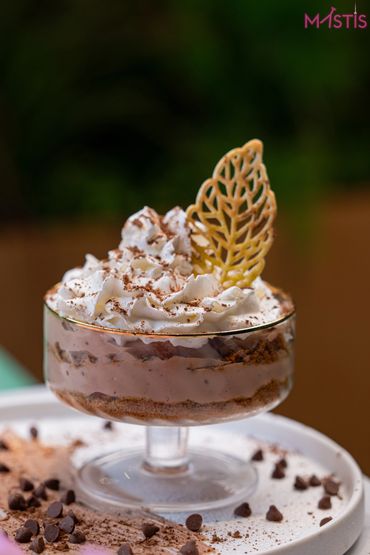 A creamy dessert with whipped topping and a decorative leaf in a glass dish.