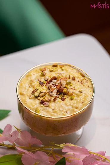 A bowl of creamy Indian kheer garnished with nuts and saffron strands.