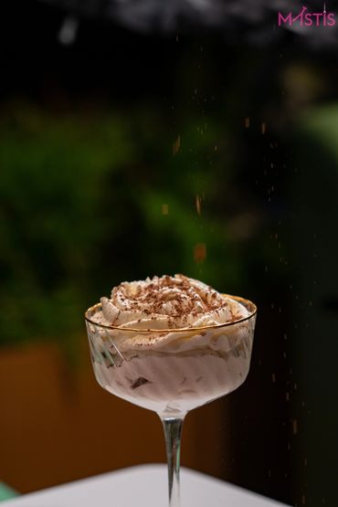 Whipped cream dessert topped with cocoa powder in a fancy glass.
