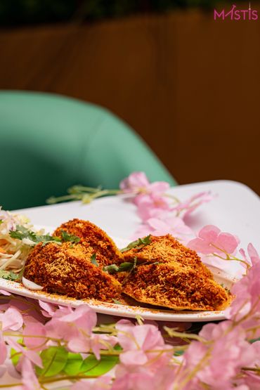 Four flavorful Indian snacks garnished with sev and coriander on a white plate.
