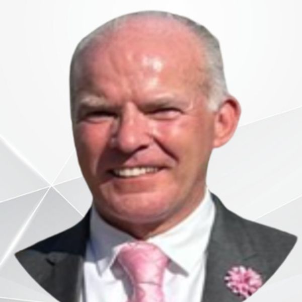 Smiling man in a suit with a pink tie and flower.